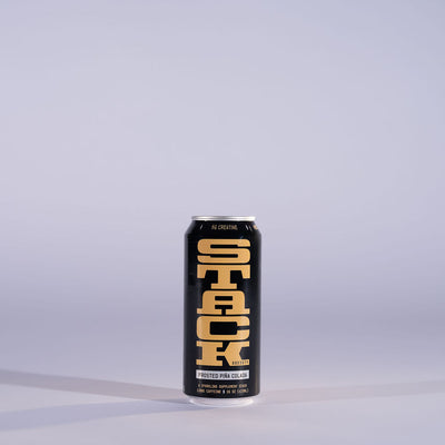 A single black aluminum can of STACK Supplement Drink with bold yellow lettering, standing upright on a light gray surface against a matching light gray background.